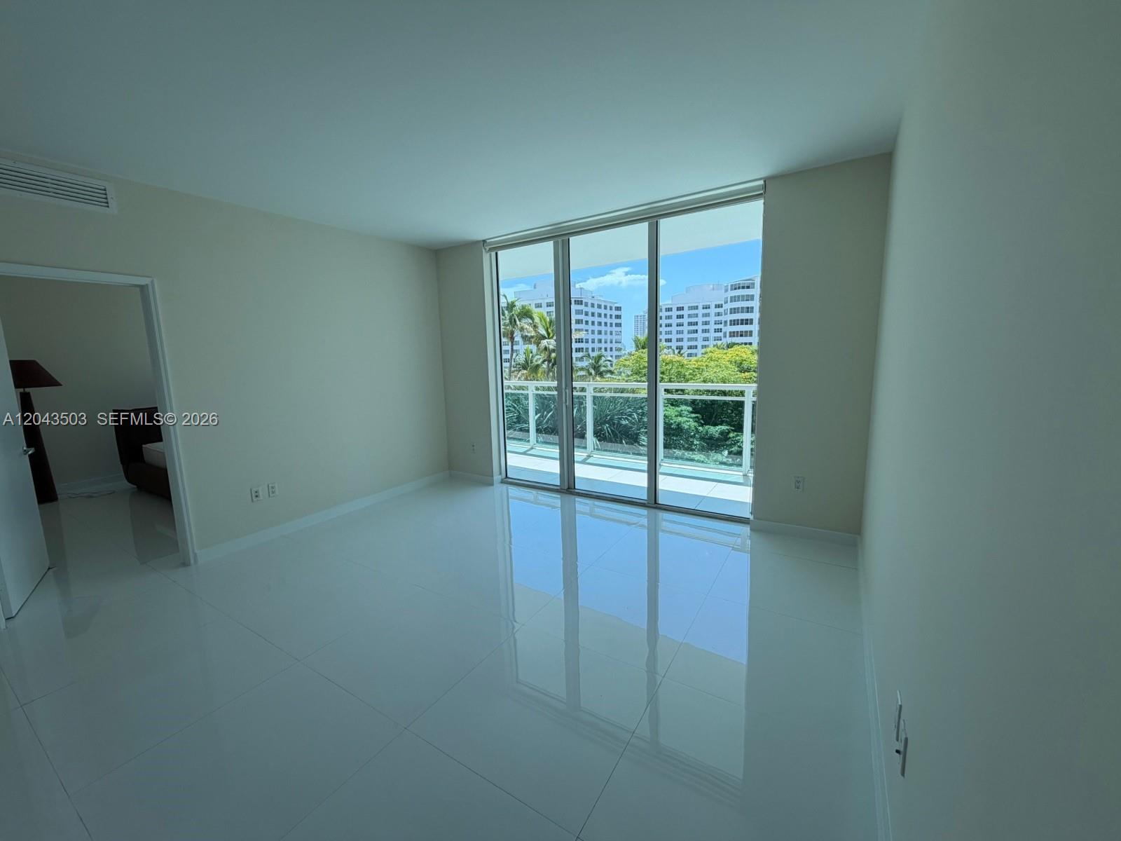 A bedroom features a dark bed, a floor lamp, and a sliding glass door — 951 Brickell Ave # 1206, Miami FL 33131, MIAMI, FL