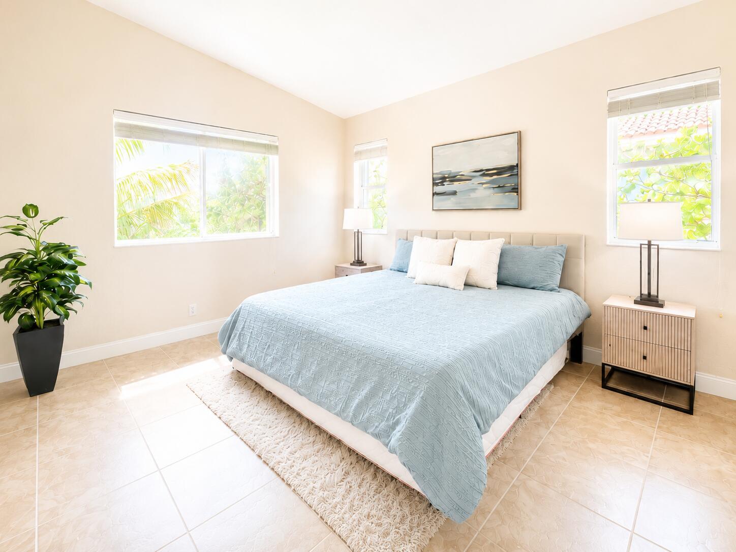 A bedroom features a blue bed, two nightstands with lamps, and tile flooring — 3022 Laurel Ridge Circle, Riviera Beach FL 33404, RIVIERA BEACH, FL