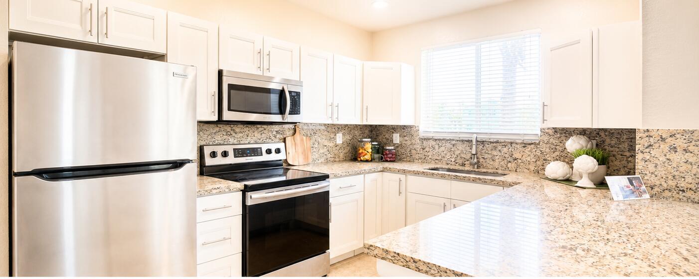A kitchen features white cabinets, stainless steel appliances, and speckled granite countertops — 3022 Laurel Ridge Circle, Riviera Beach FL 33404, RIVIERA BEACH, FL