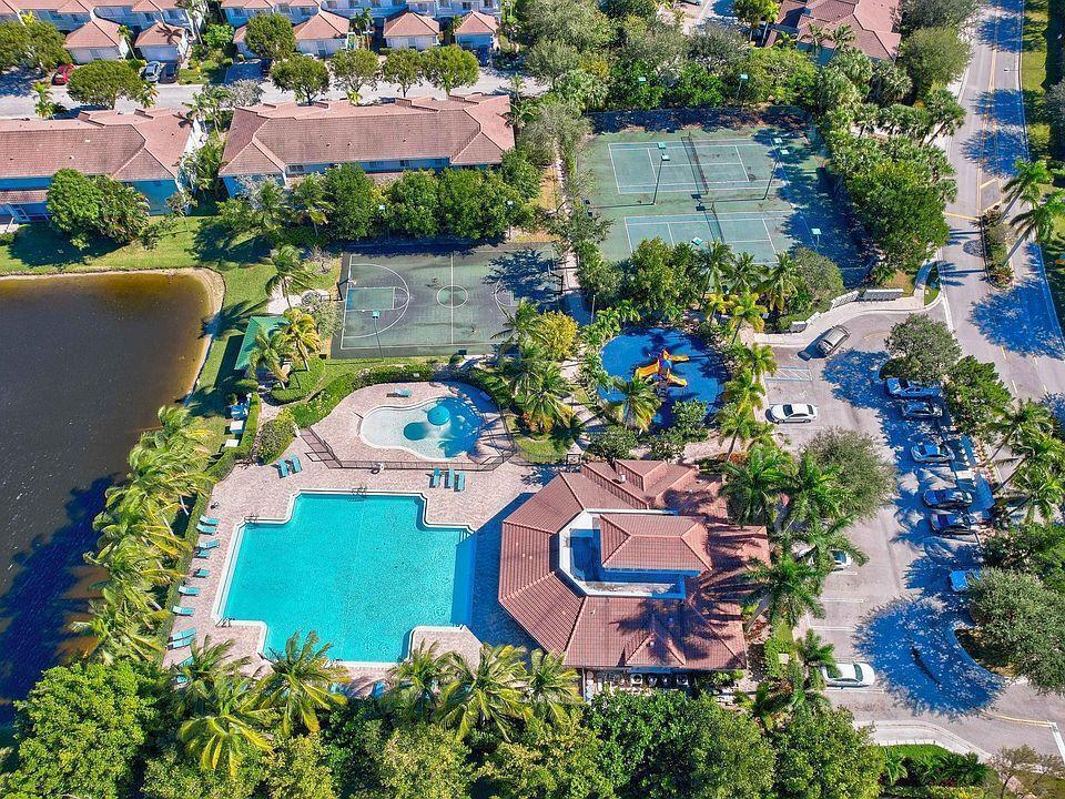 An aerial view shows a community pool, tennis courts, basketball court, and clubhouse with parking — 3022 Laurel Ridge Circle, Riviera Beach FL 33404, RIVIERA BEACH, FL