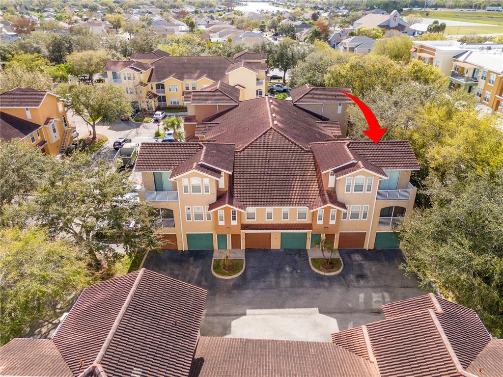 An aerial view shows a multi-story residential building with a red tile roof — 12102 POPPY FIELD LANE UNIT 107, ORLANDO, FL