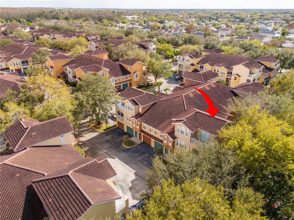 An aerial view shows a multi-story residential building with a red tile roof and garages — 12102 POPPY FIELD LANE UNIT 107, ORLANDO, FL