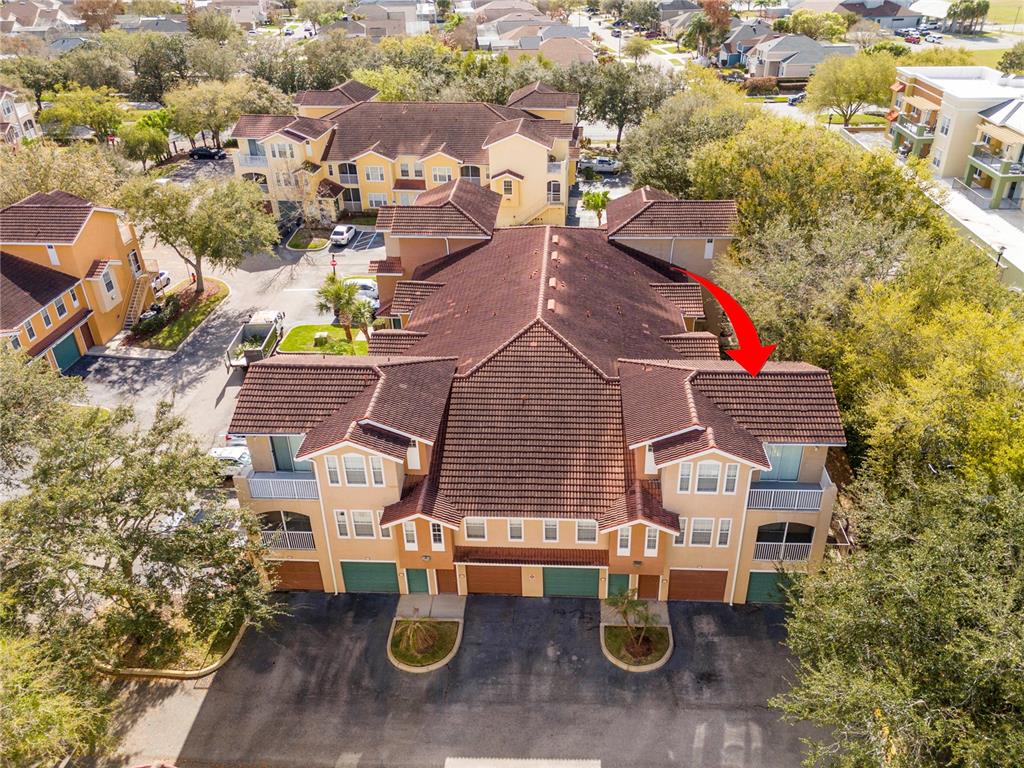 An aerial view shows a multi-story apartment building with a brown tile roof — 12102 POPPY FIELD LANE UNIT 107, ORLANDO, FL