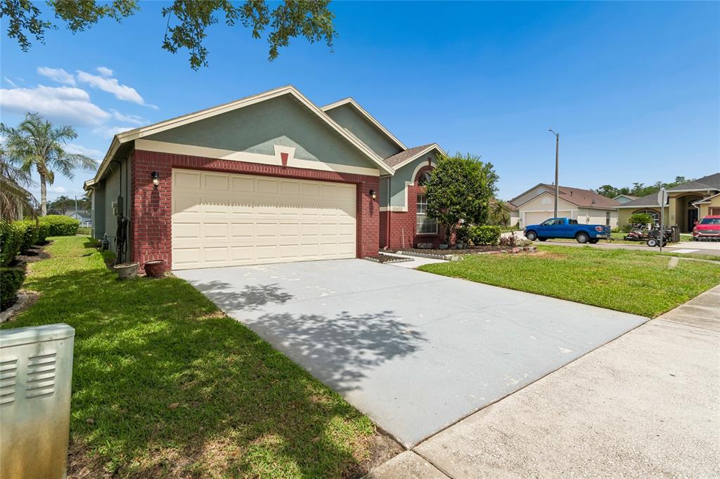 A single-story house with a two-car garage, brick accents, and a concrete driveway — 30600 NICKERSON LOOP, WESLEY CHAPEL, FL
