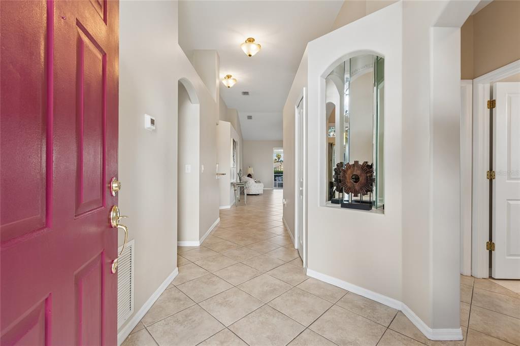 A foyer with a pink front door, tile flooring, and an arched wall niche — 30600 NICKERSON LOOP, WESLEY CHAPEL, FL