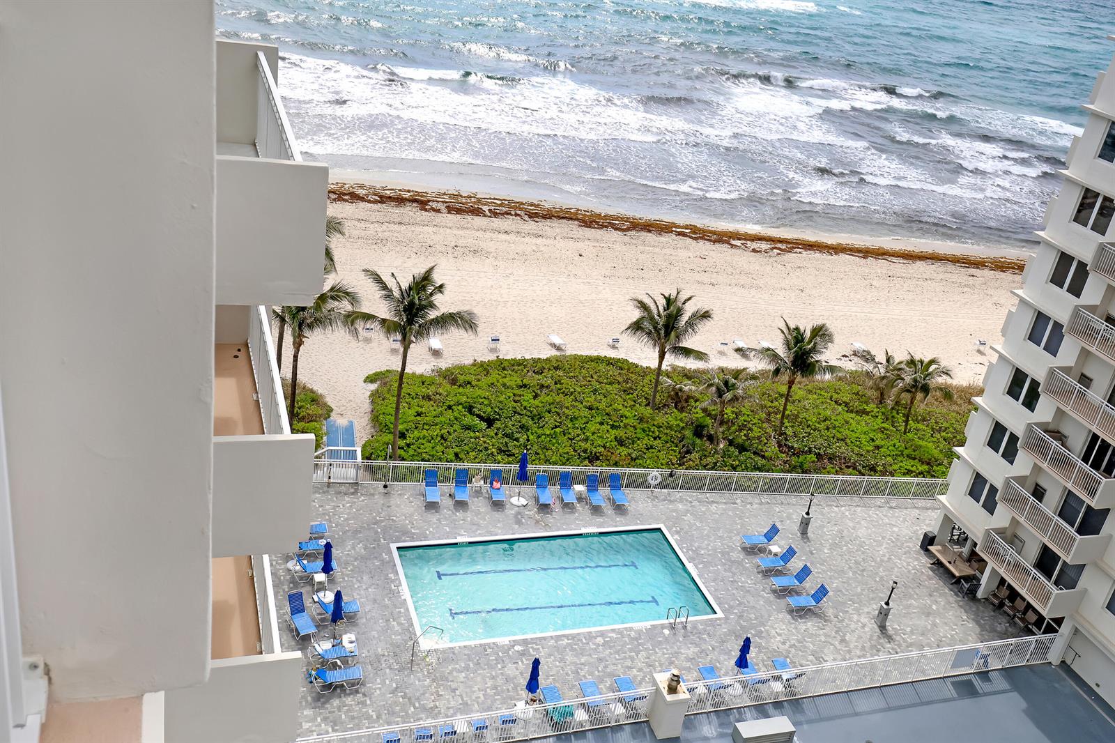 An elevated view shows a swimming pool on a patio overlooking a beach and ocean — 3221 S Ocean Boulevard # 1003, Highland Beach FL 33487, HIGHLAND BEACH, FL