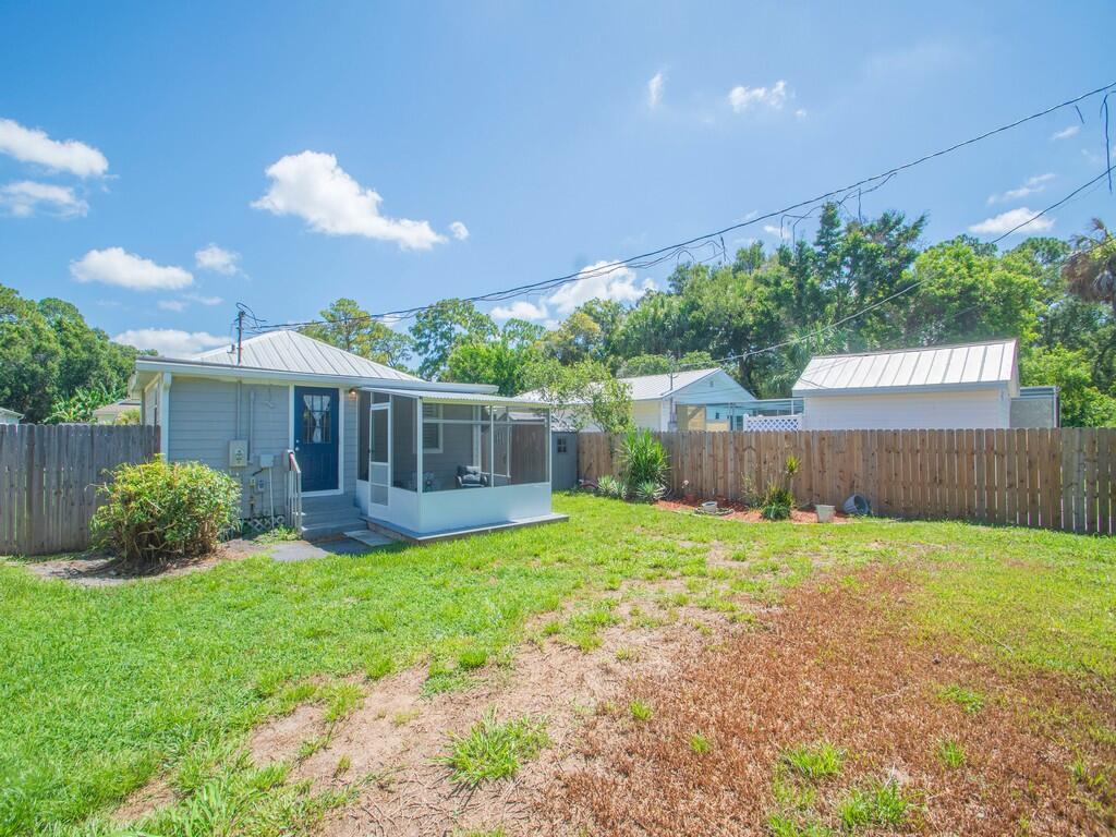 A backyard view of a house with a screened-in porch and a wooden fence — 3535 3rd Street, Vero Beach FL 32968, VERO BEACH, FL