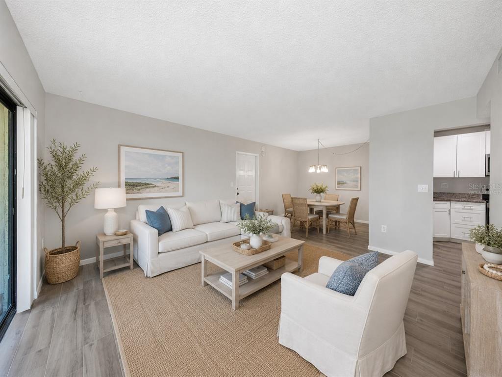 A living room and dining area with light wood floors, neutral furniture, and white walls — 3166 LAKE PINE WAY S UNIT H1, TARPON SPRINGS, FL