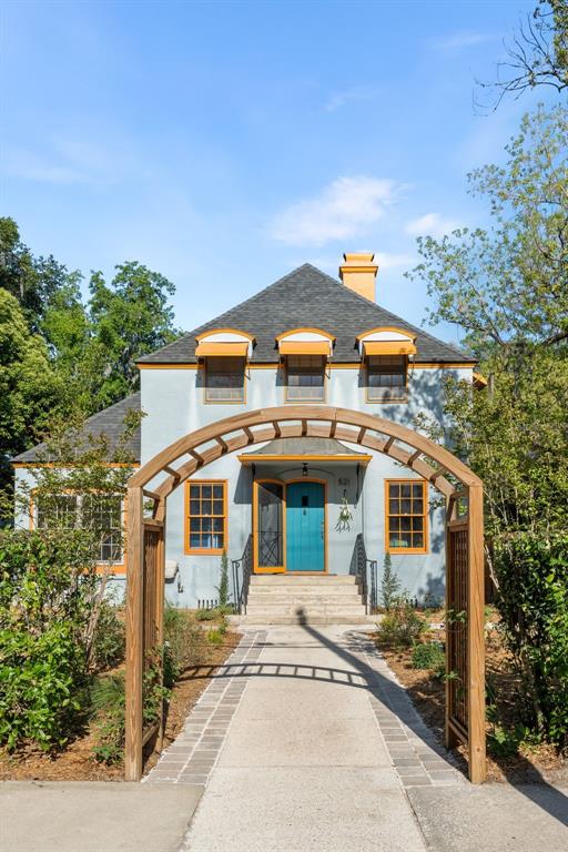 A light blue two-story house with orange trim viewed through a wooden garden archway — 521 NE 6TH STREET, GAINESVILLE, FL