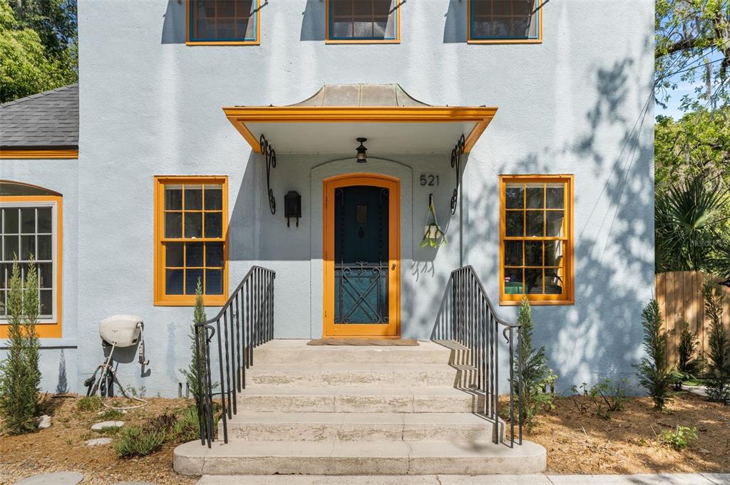 A light blue house exterior features a front porch with orange trim and concrete steps — 521 NE 6TH STREET, GAINESVILLE, FL