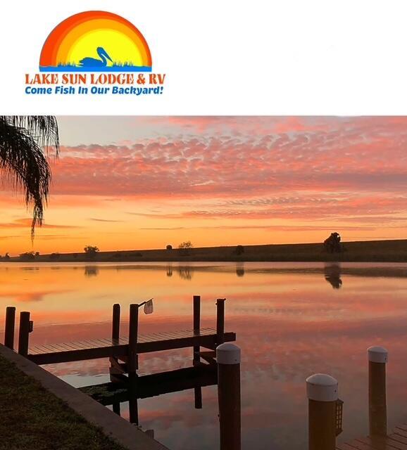 A wooden dock extends into a calm lake under a vibrant orange and pink sunset — 8680 Us Highway 441 SE, Okeechobee FL 34974, OKEECHOBEE, FL