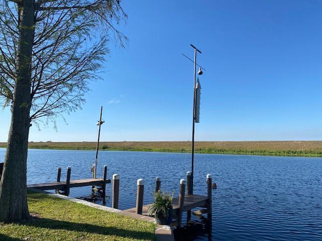 A wooden dock extends into a calm lake under a clear blue sky — 8680 Us Highway 441 SE, Okeechobee FL 34974, OKEECHOBEE, FL