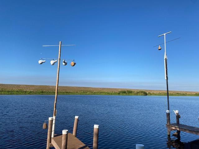 Two wooden poles with hanging bird gourds stand above a dock on a calm lake — 8680 Us Highway 441 SE, Okeechobee FL 34974, OKEECHOBEE, FL