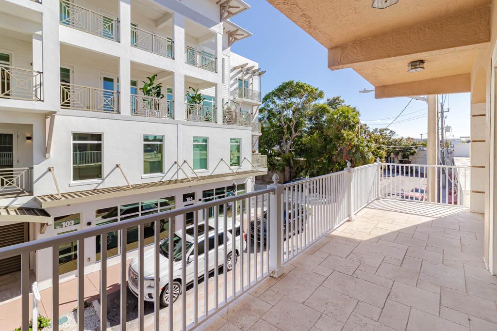 An open-concept living area features white marble-look tile flooring, a ceiling fan, and a kitchen — 47 SW Osceola Street # 206, Stuart FL 34994, STUART, FL