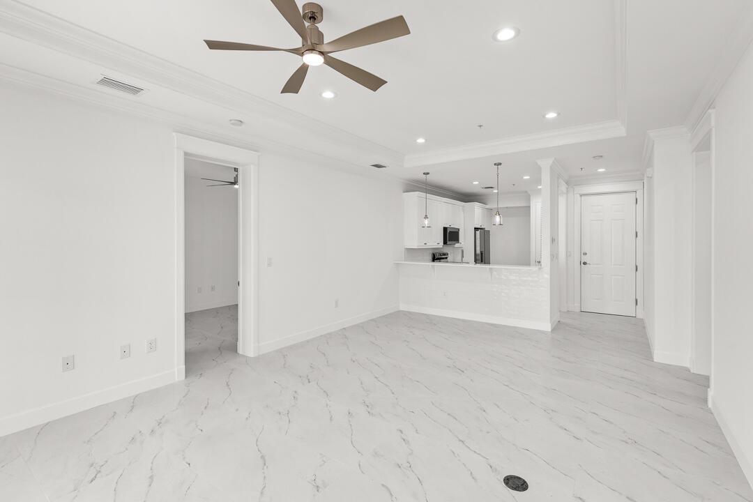 An empty room features white marble-look tile flooring, a tray ceiling, and sliding glass doors — 47 SW Osceola Street # 206, Stuart FL 34994, STUART, FL