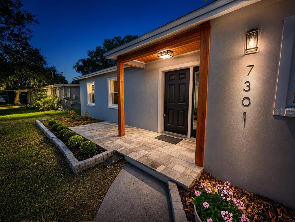 A gray house exterior features a paved front porch with wood beams and modern lighting — 7301 S WEST SHORE BOULEVARD, TAMPA, FL