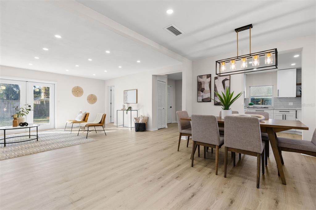 A bright, open-concept dining and living area features light wood flooring and modern light fixtures — 7301 S WEST SHORE BOULEVARD, TAMPA, FL