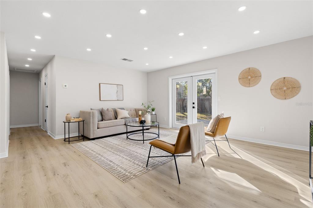 A living room features light wood flooring, a beige sofa, two leather chairs, and recessed lighting — 7301 S WEST SHORE BOULEVARD, TAMPA, FL