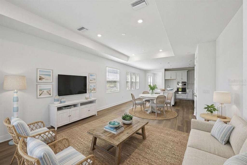 A bright, open-concept living and dining area features white walls, wood flooring, and coastal decor — 9669 CRYSTAL ISLES CIRCLE, SARASOTA, FL