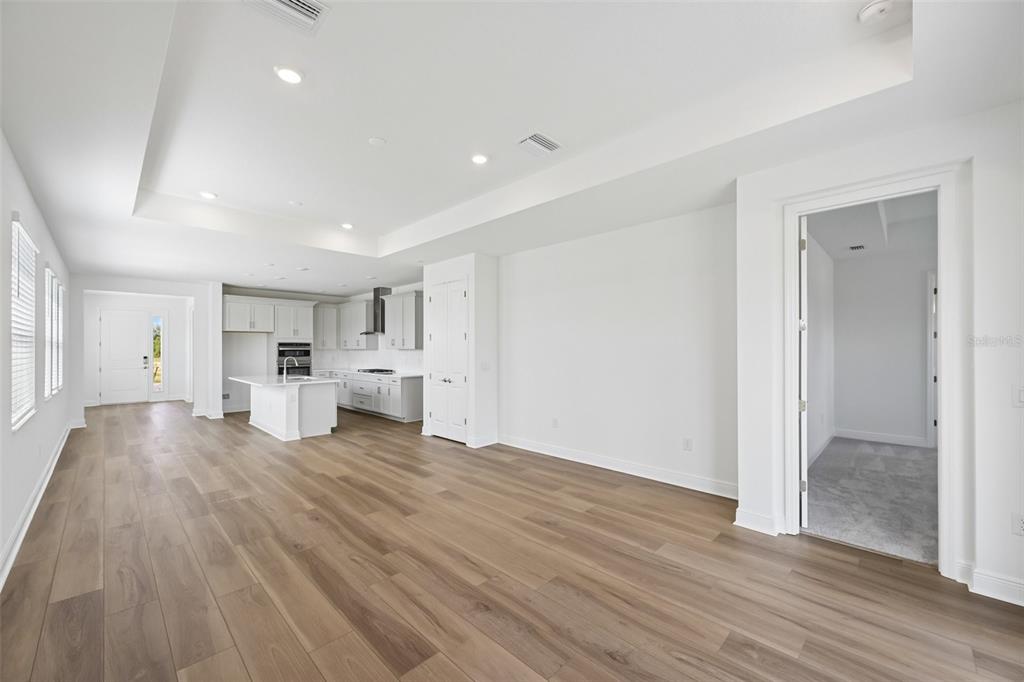 A bright, open-concept kitchen and living area with white cabinetry and light wood flooring — 9669 CRYSTAL ISLES CIRCLE, SARASOTA, FL