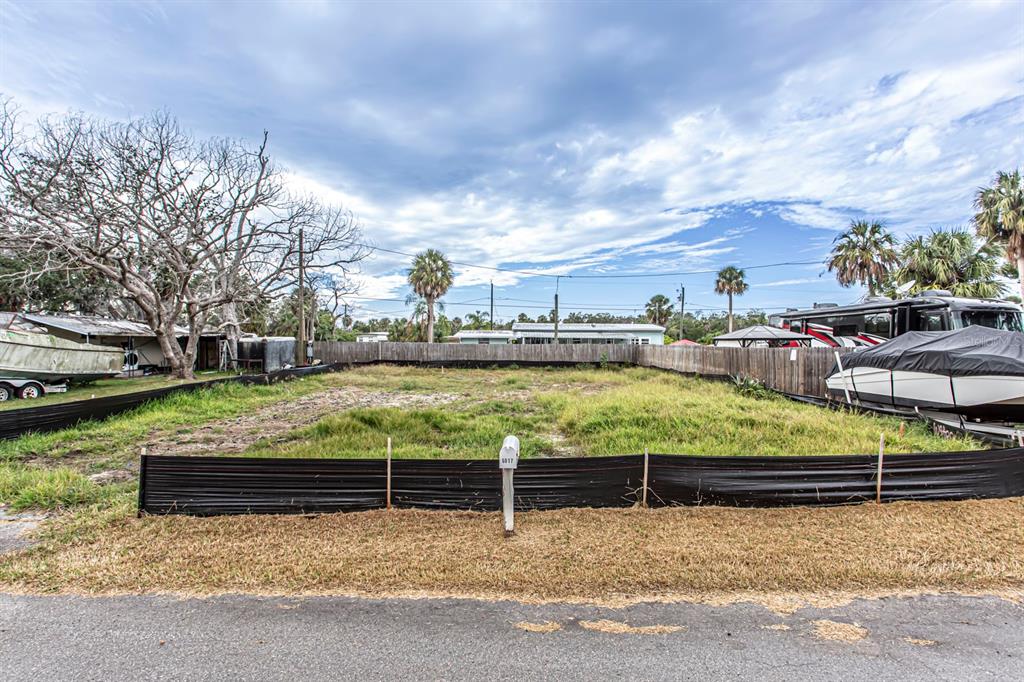 A vacant, grassy residential lot is enclosed by a wooden fence and black silt fencing — 6813 GARDEN DRIVE, NEW PORT RICHEY, FL