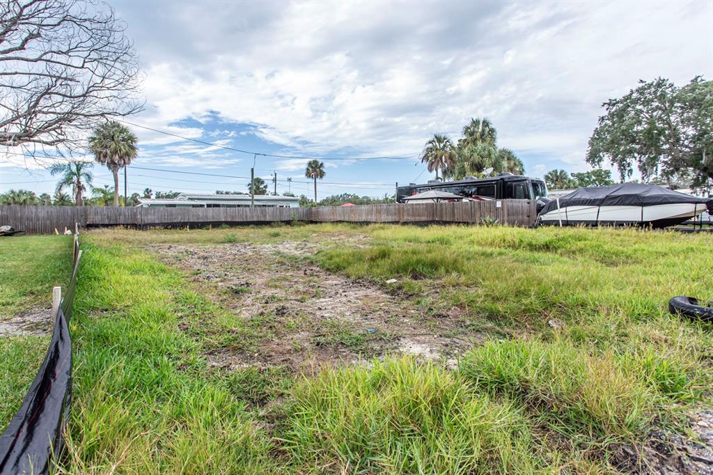 A vacant, grassy lot is enclosed by a wooden fence with a boat parked nearby — 6813 GARDEN DRIVE, NEW PORT RICHEY, FL