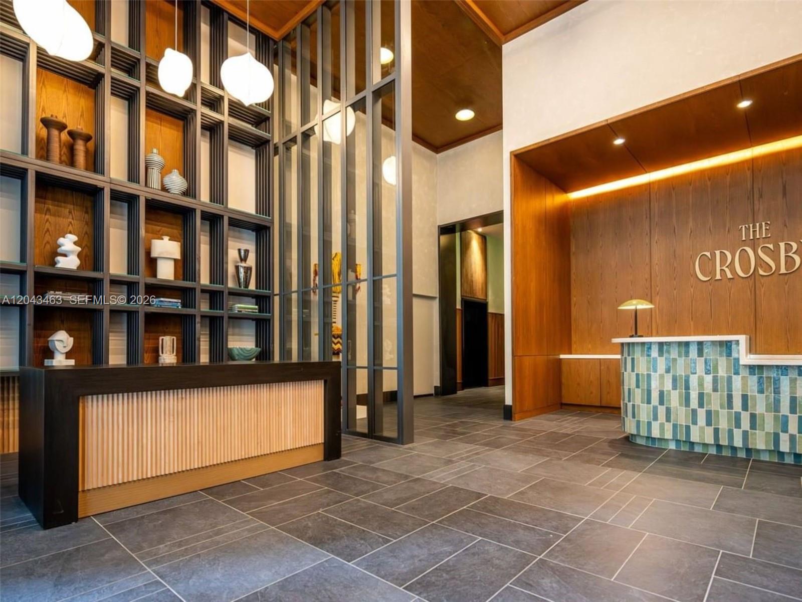 A modern lobby features a reception desk, wood-paneled walls, decorative shelving, and large floor tiles — 11 NE 6th St # 1509, Miami FL 33132, MIAMI, FL