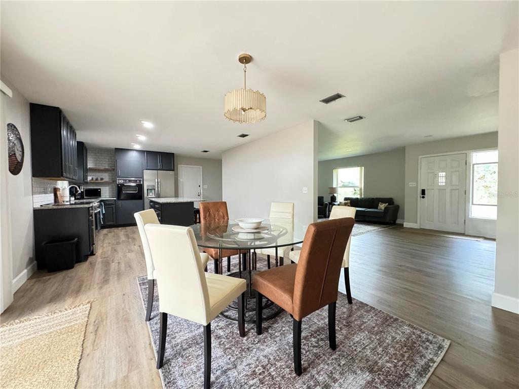 An open-concept dining area with a glass table, chairs, and an adjacent modern kitchen — 1836 NW 40TH TERRACE, GAINESVILLE, FL