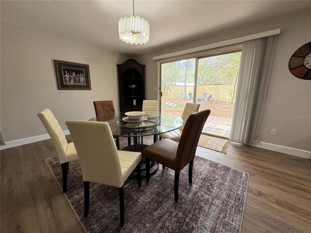 A dining room features a glass-topped table, upholstered chairs, a chandelier, and sliding glass doors — 1836 NW 40TH TERRACE, GAINESVILLE, FL