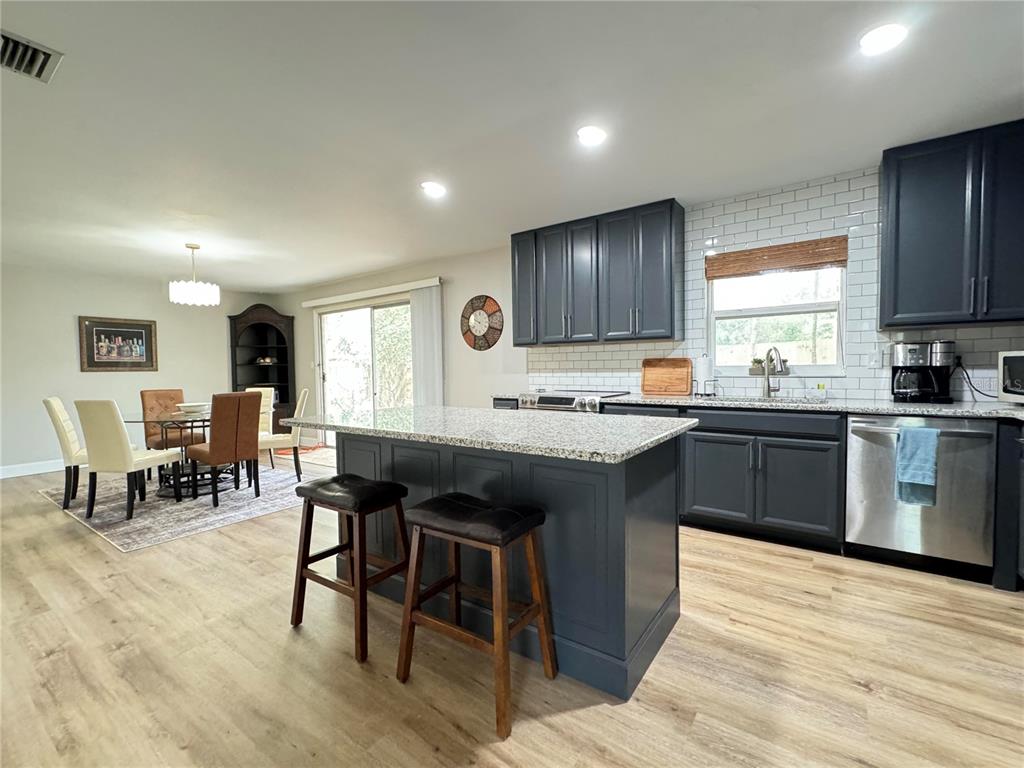 A kitchen with dark cabinets, a granite-topped island, and light wood flooring — 1836 NW 40TH TERRACE, GAINESVILLE, FL