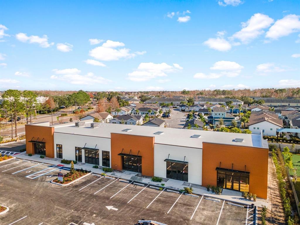 An aerial view of a modern, single-story commercial building with a parking lot in front — 16232 REDSTONE WAY, ODESSA, FL