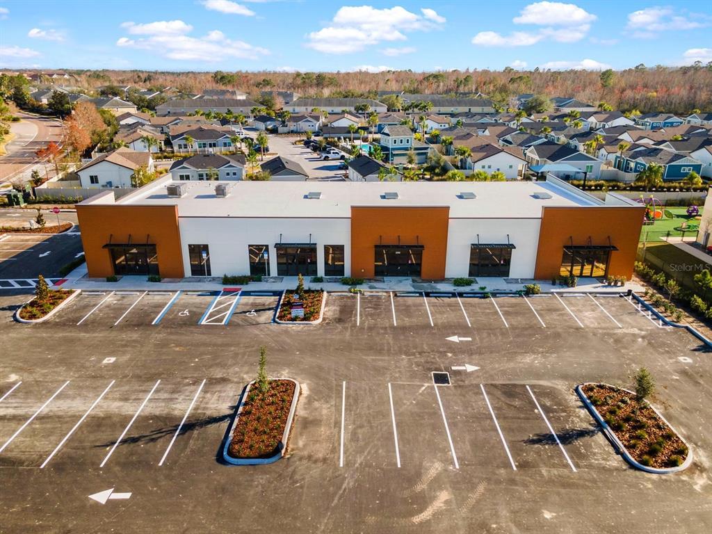 An aerial view shows a modern commercial building with a parking lot in front — 16232 REDSTONE WAY, ODESSA, FL