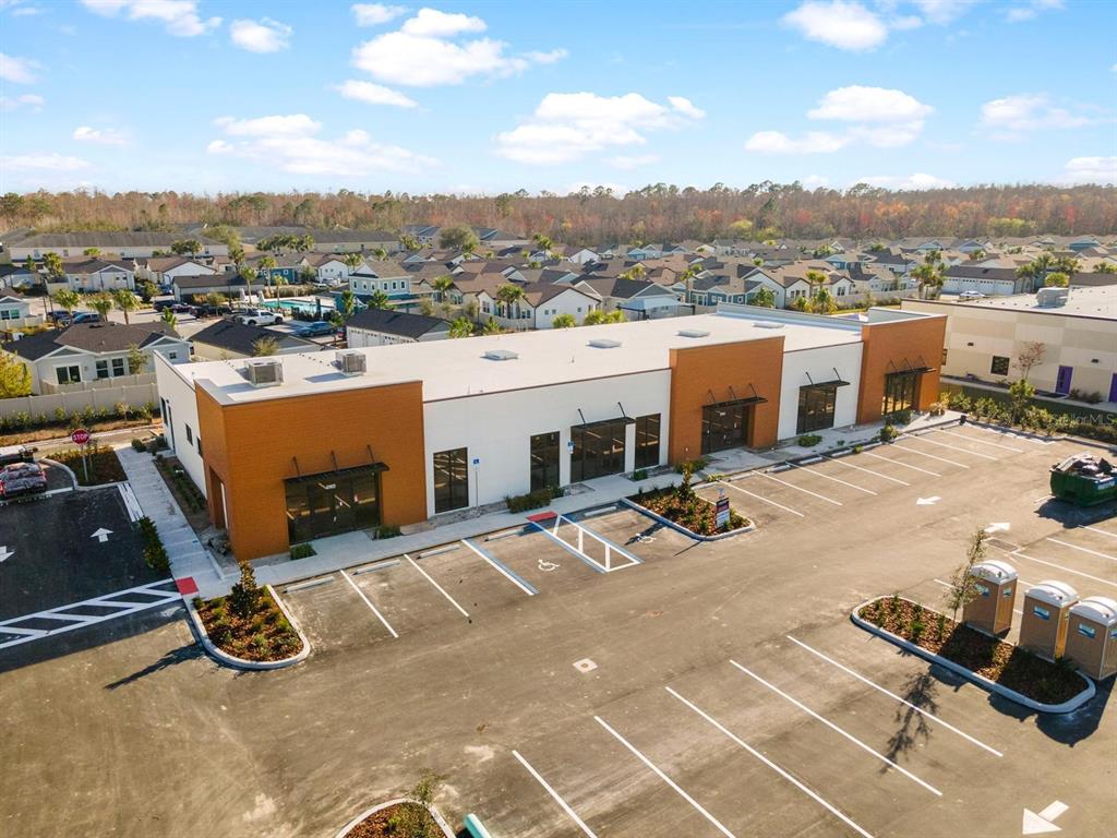 An aerial view shows a modern commercial building with a parking lot and surrounding neighborhood — 16232 REDSTONE WAY, ODESSA, FL