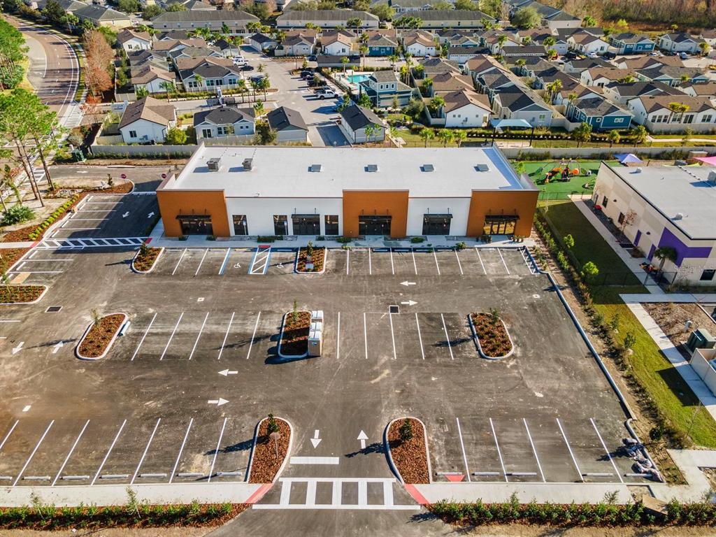 An aerial view shows a commercial building with a large parking lot in a residential neighborhood — 16232 REDSTONE WAY, ODESSA, FL