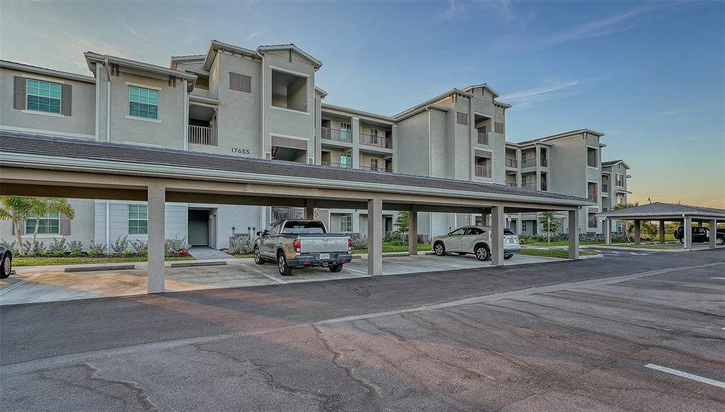 A multi-story apartment building features a covered parking structure in the foreground — 17655 OPAL SAND DRIVE UNIT 302, VENICE, FL