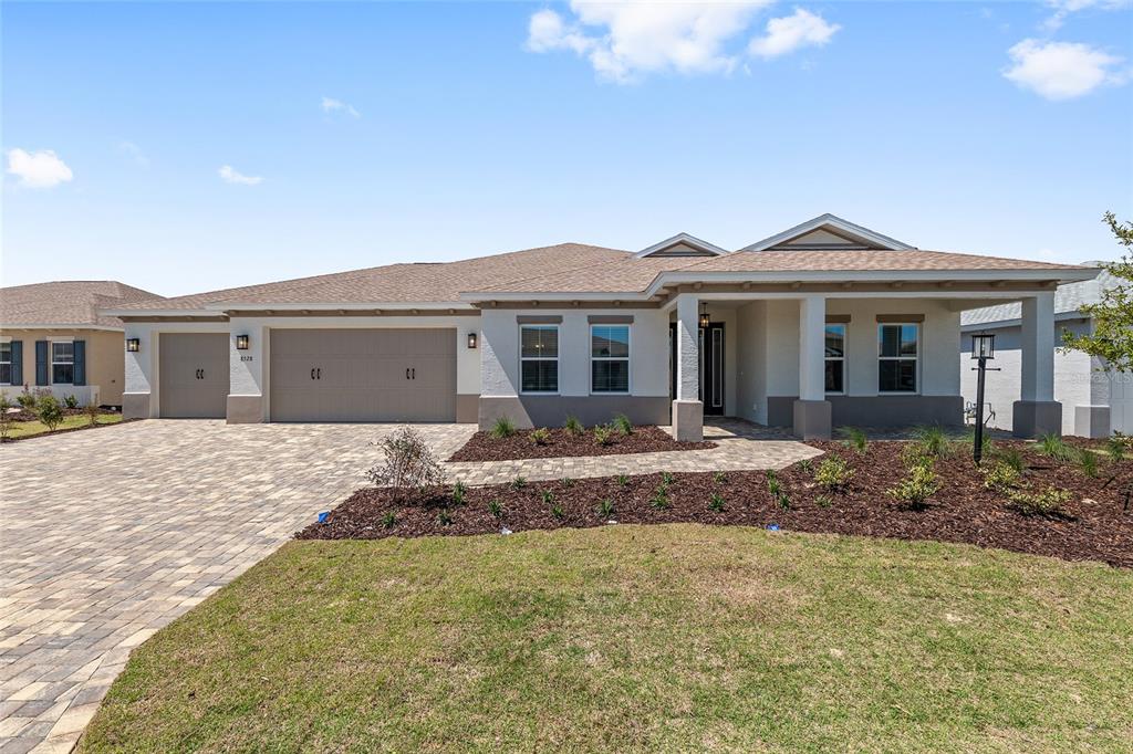The exterior of a single-story house features a paved driveway, a three-car garage, and landscaping — 8528 SW 101ST AVENUE, OCALA, FL