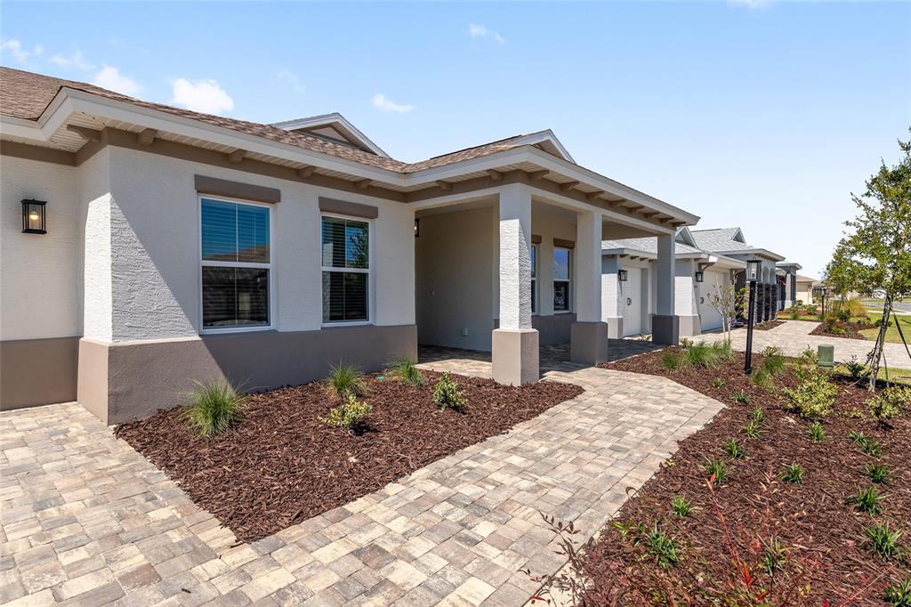 A single-story house exterior features a covered entryway, stone-paver walkway, and landscaped mulch beds — 8528 SW 101ST AVENUE, OCALA, FL