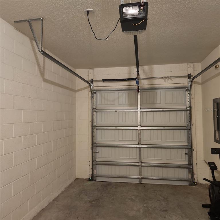 A garage with a concrete floor, white block walls, and a sectional overhead door — 1636 THICKET AVENUE, DAVENPORT, FL