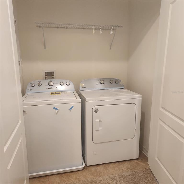 A laundry closet contains a white top-loading washing machine and a matching dryer — 1636 THICKET AVENUE, DAVENPORT, FL