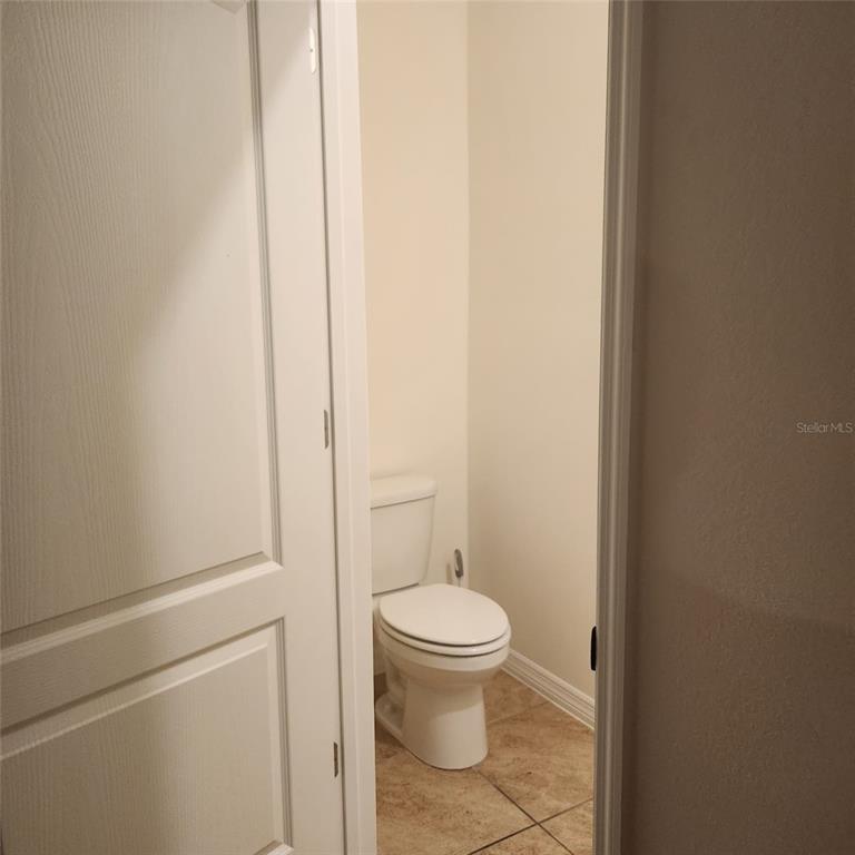 A small bathroom with a white toilet and light-colored tile flooring — 1636 THICKET AVENUE, DAVENPORT, FL