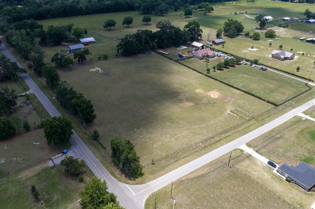 An aerial view shows a large, fenced, grassy lot situated at a road intersection — TBD NE 106TH STREET, ANTHONY, FL