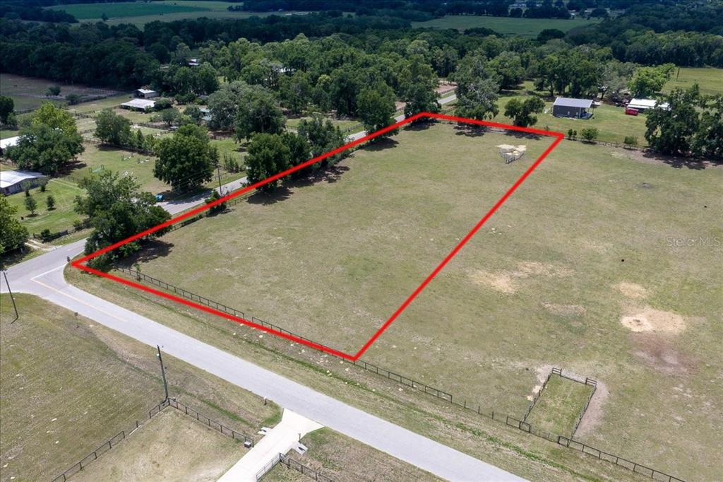 An aerial view shows a fenced, rectangular plot of grassy land bordering a paved road — TBD NE 106TH STREET, ANTHONY, FL