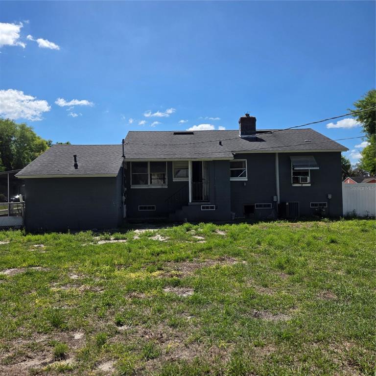 A gray single-story house with a white fence, a palm tree, and a gravel driveway — 2306 BUTLER STREET, LEESBURG, FL