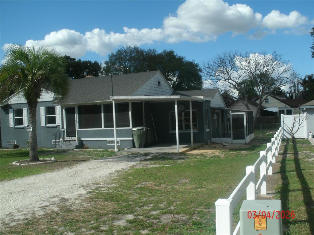 The exterior of a gray painted brick house features three windows with metal slatted awnings — 2306 BUTLER STREET, LEESBURG, FL