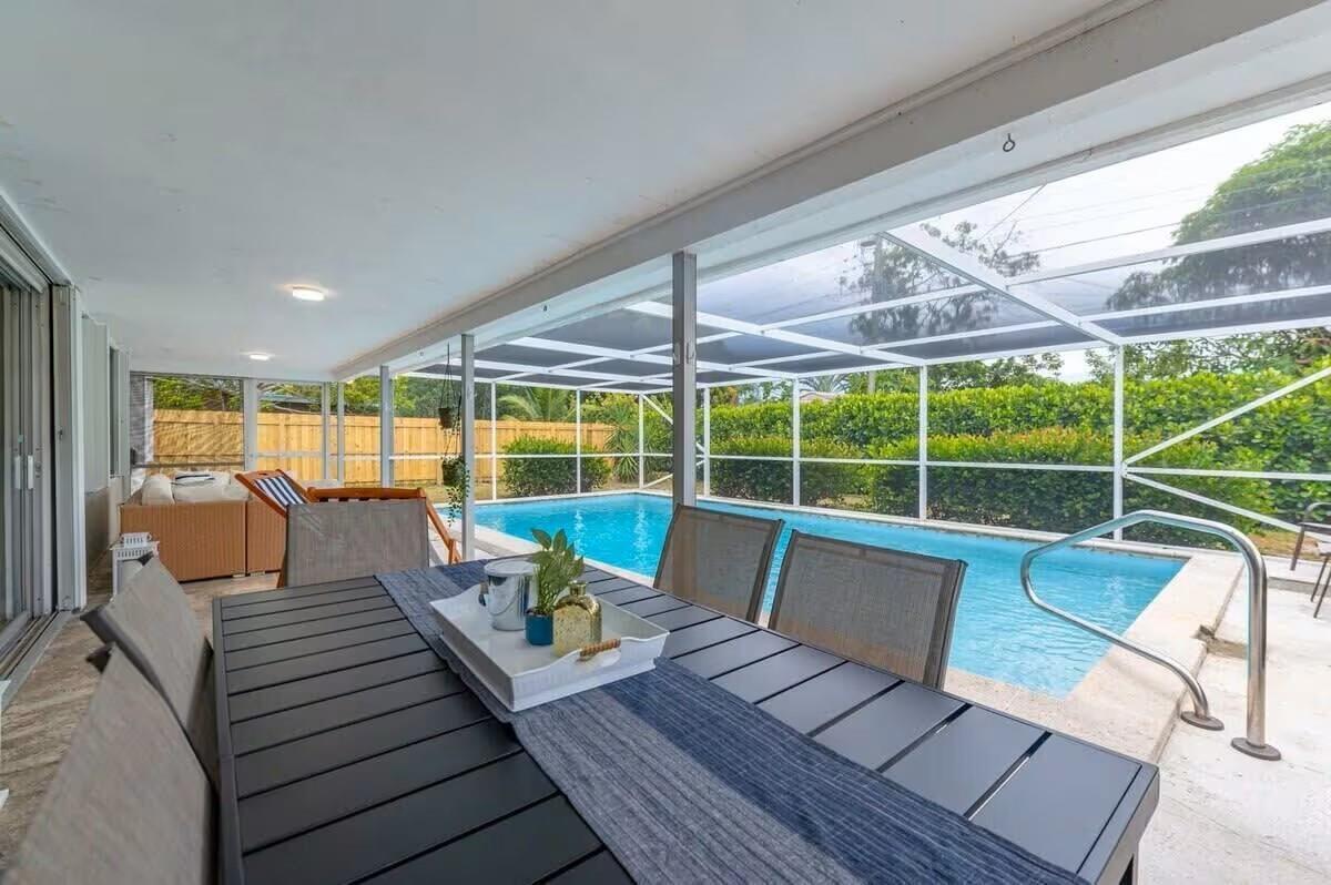 A covered patio with a dining table overlooks a screened-in swimming pool and backyard — 176 SE 27th Place, Boynton Beach FL 33435, BOYNTON BEACH, FL