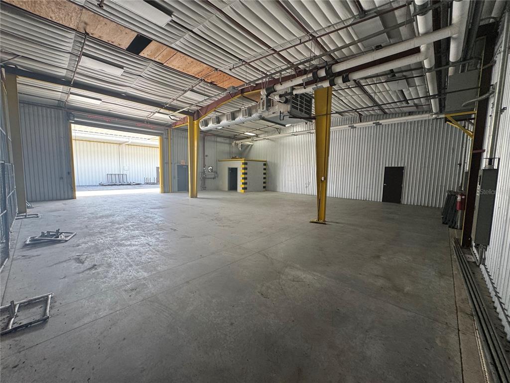 An empty industrial warehouse space features concrete floors, metal walls, and exposed ceiling rafters — 2251 TOPLINE WAY UNIT 1, BROOKSVILLE, FL