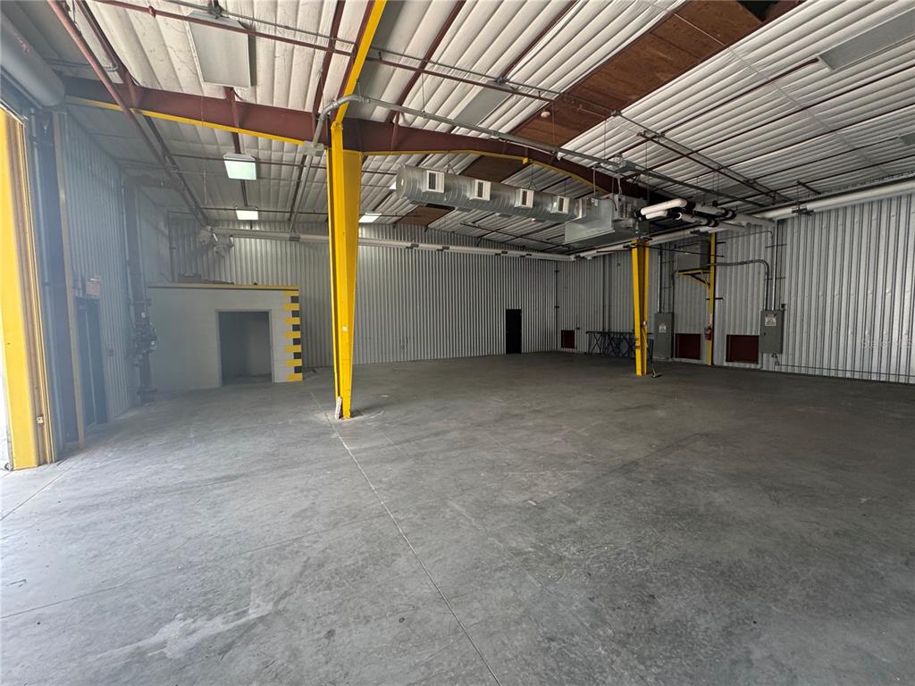 An interior view of a large industrial warehouse space with concrete floors and yellow support columns — 2251 TOPLINE WAY UNIT 1, BROOKSVILLE, FL