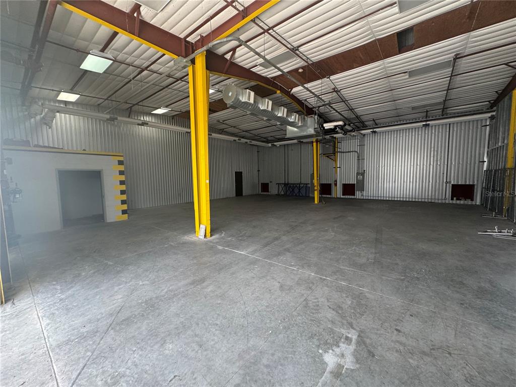 An empty industrial warehouse space features concrete floors, metal walls, and exposed yellow support beams — 2251 TOPLINE WAY UNIT 1, BROOKSVILLE, FL
