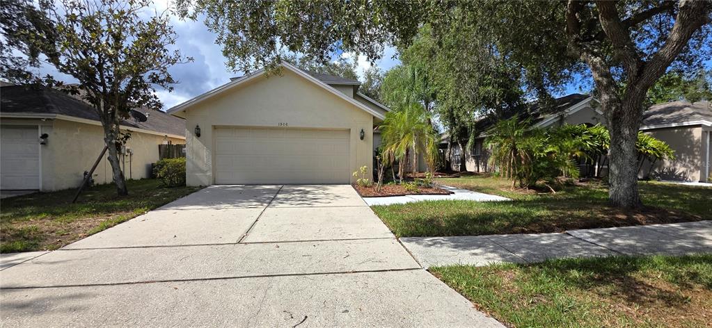 A single-story house with a beige exterior, a two-car garage, and a concrete driveway — 1506 SCOTCH PINE DRIVE, BRANDON, FL