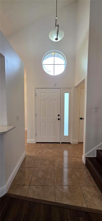 An entryway with a vaulted ceiling, a circular window, a white door, and tiled flooring — 1506 SCOTCH PINE DRIVE, BRANDON, FL